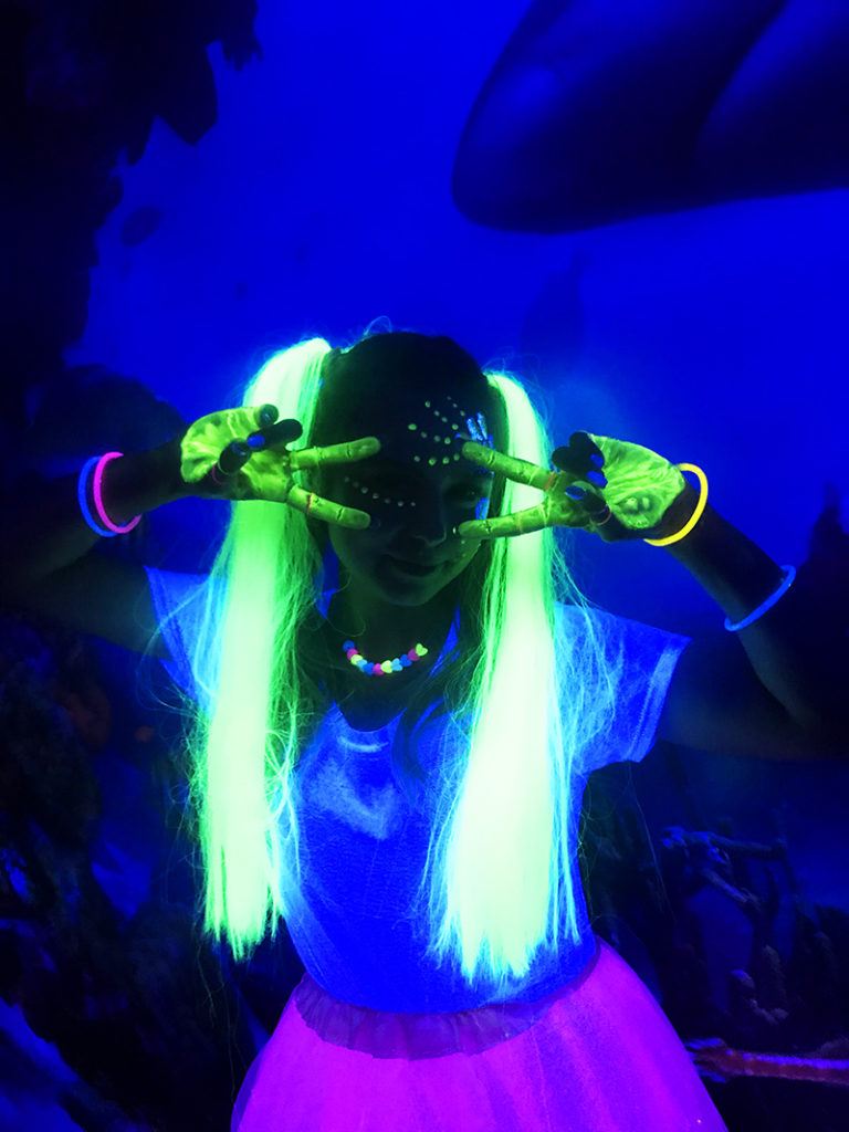 Dziewczyna pomalowana farbami fluorescencyjnymi świecąca w świetle ultrafioletowym.